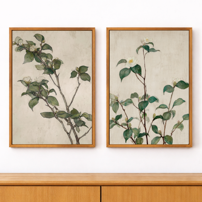 Two framed botanical prints of green leaves and branches on a white wall.